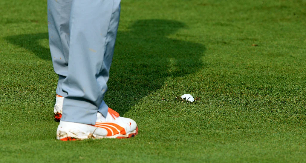 A golf ball at the feet of Rickie Fowler of the United States is seen embedded in a fairway during the final round of the 96th PGA Championship at Valhalla Golf Club